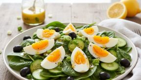 סלט תרד וביצה עם זיתים ומלפפוצים בצלחת לבנה