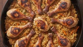 קדירת שוקי עוף צלויות על מצע אורז עם גזר ובצל במחבת ברזל יצוק במבט מלמעלה